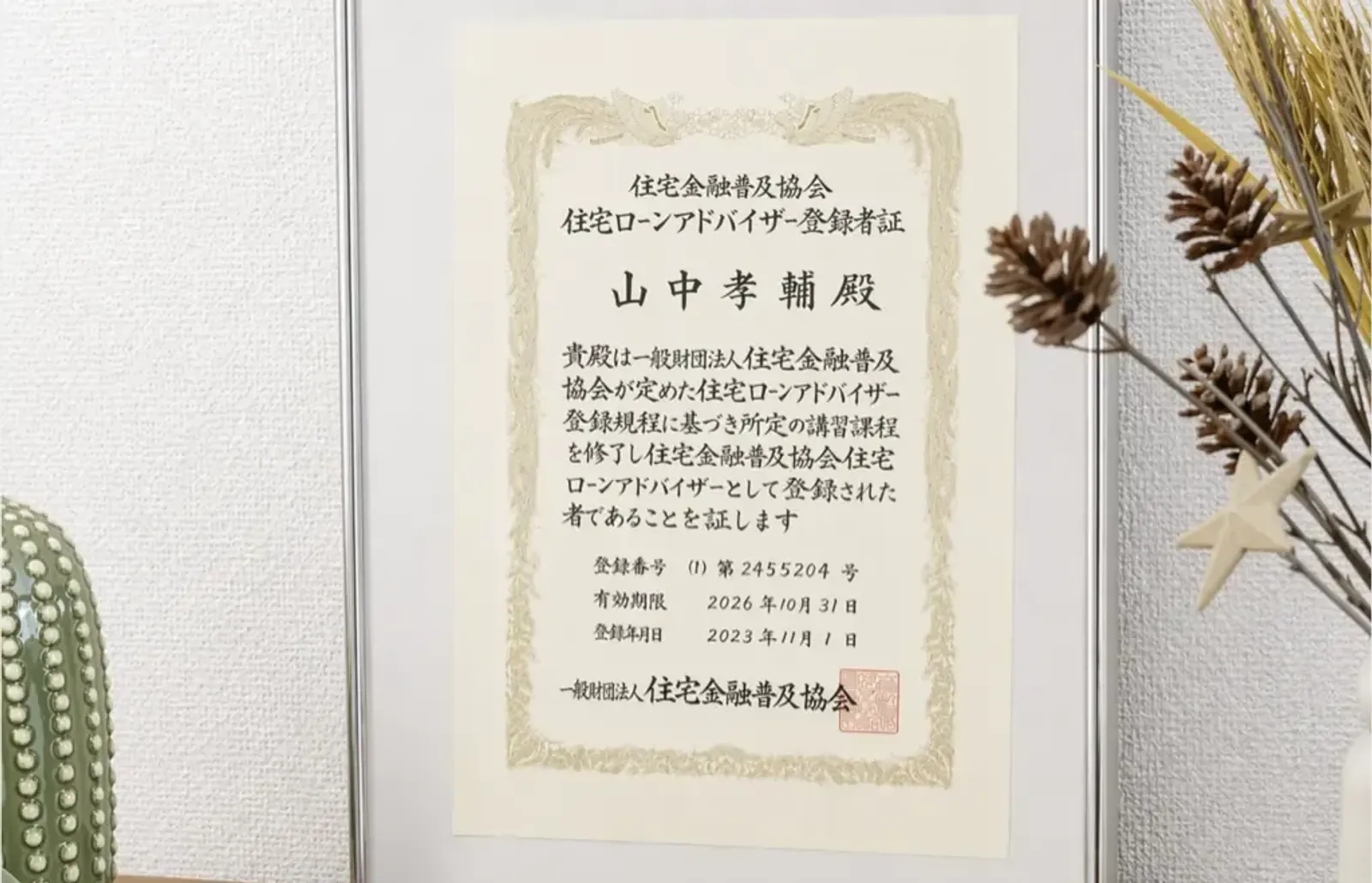 Certificado de registro como 住宅ローンアドバイザー, emoldurado sobre uma mesa